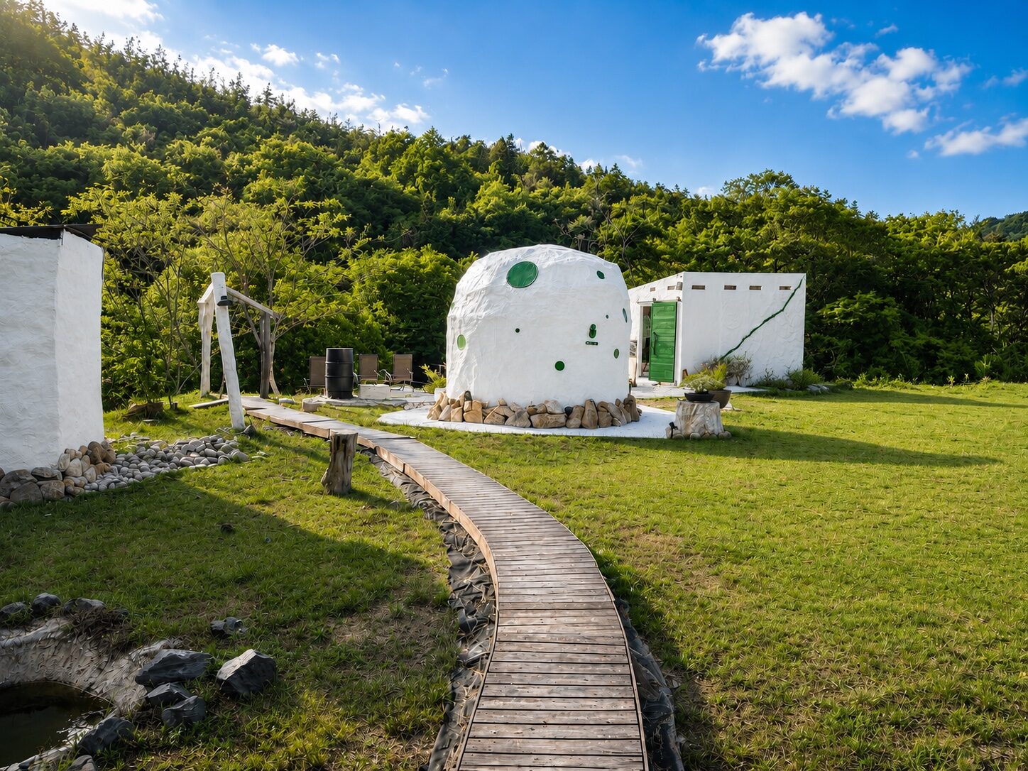 芝生の敷地に伸びる木道と、白いドーム型のサウナ小屋